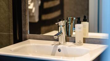 A bathroom with a white sink, a mirror, and toiletries on the counter.