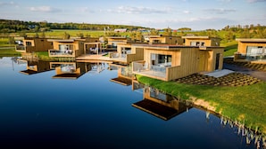 Ein modernes Anwesen am Wasser mit mehreren Holzbauten, jeweils mit Balkonen und großen Fenstern.