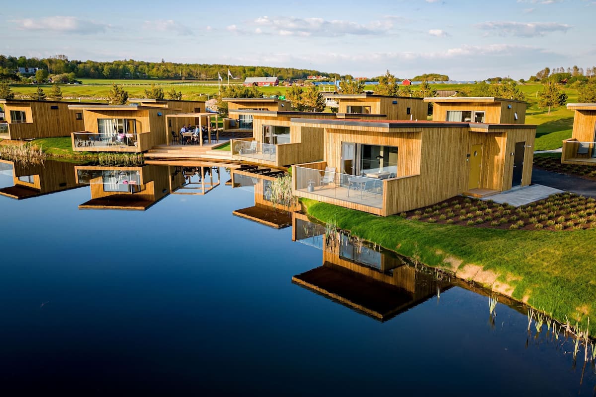 En modern fastighet vid vattnet med flera trähus, där varje hus har balkonger och stora fönster.
