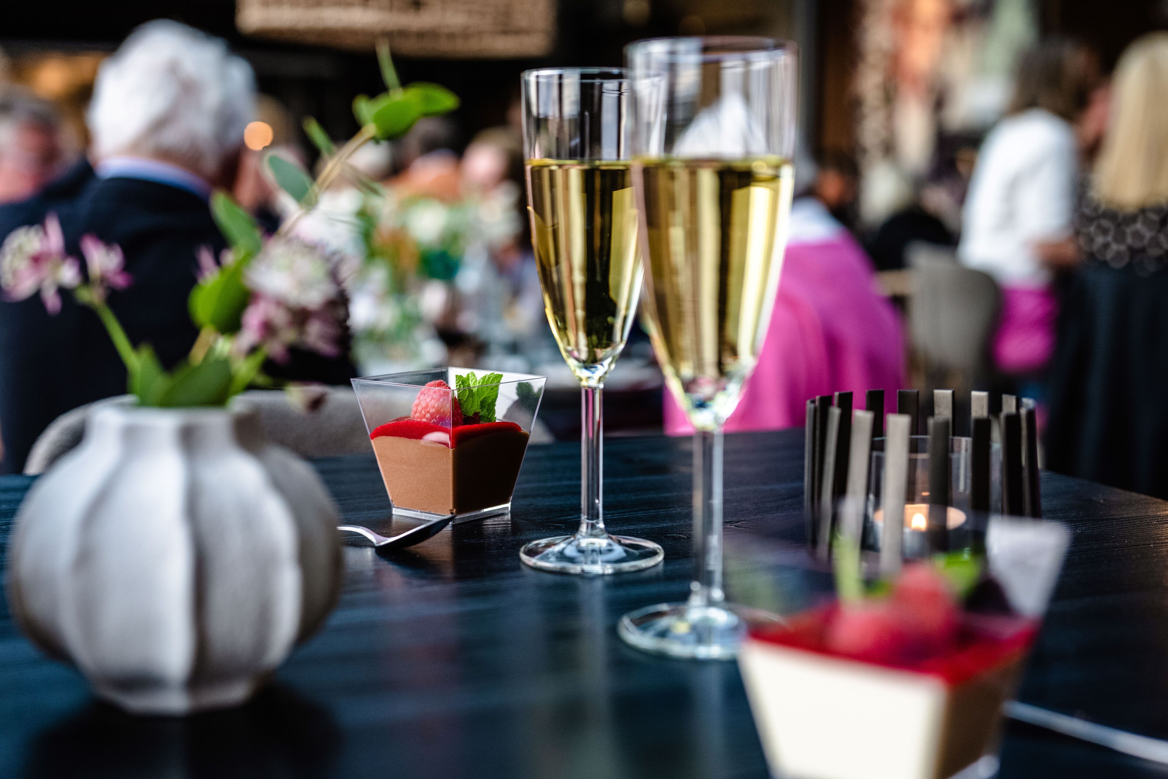Ett bord med en dessert, två glas champagne och ett ljus.