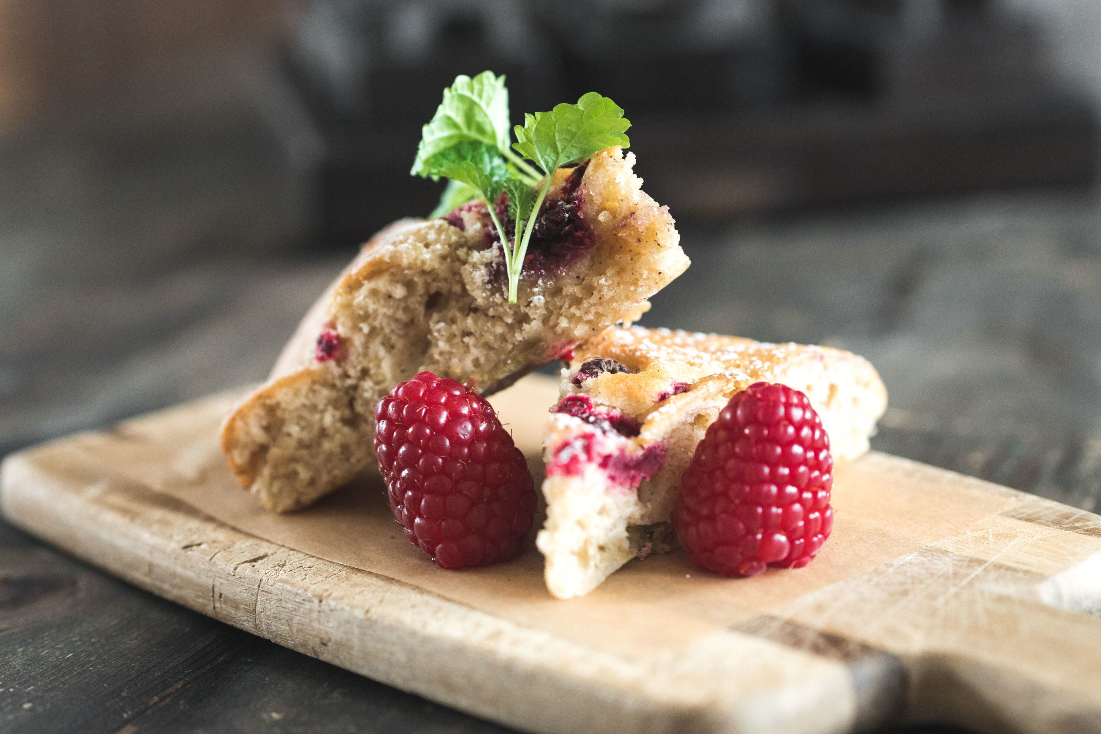 A dessert with raspberries and mint on a wooden board.