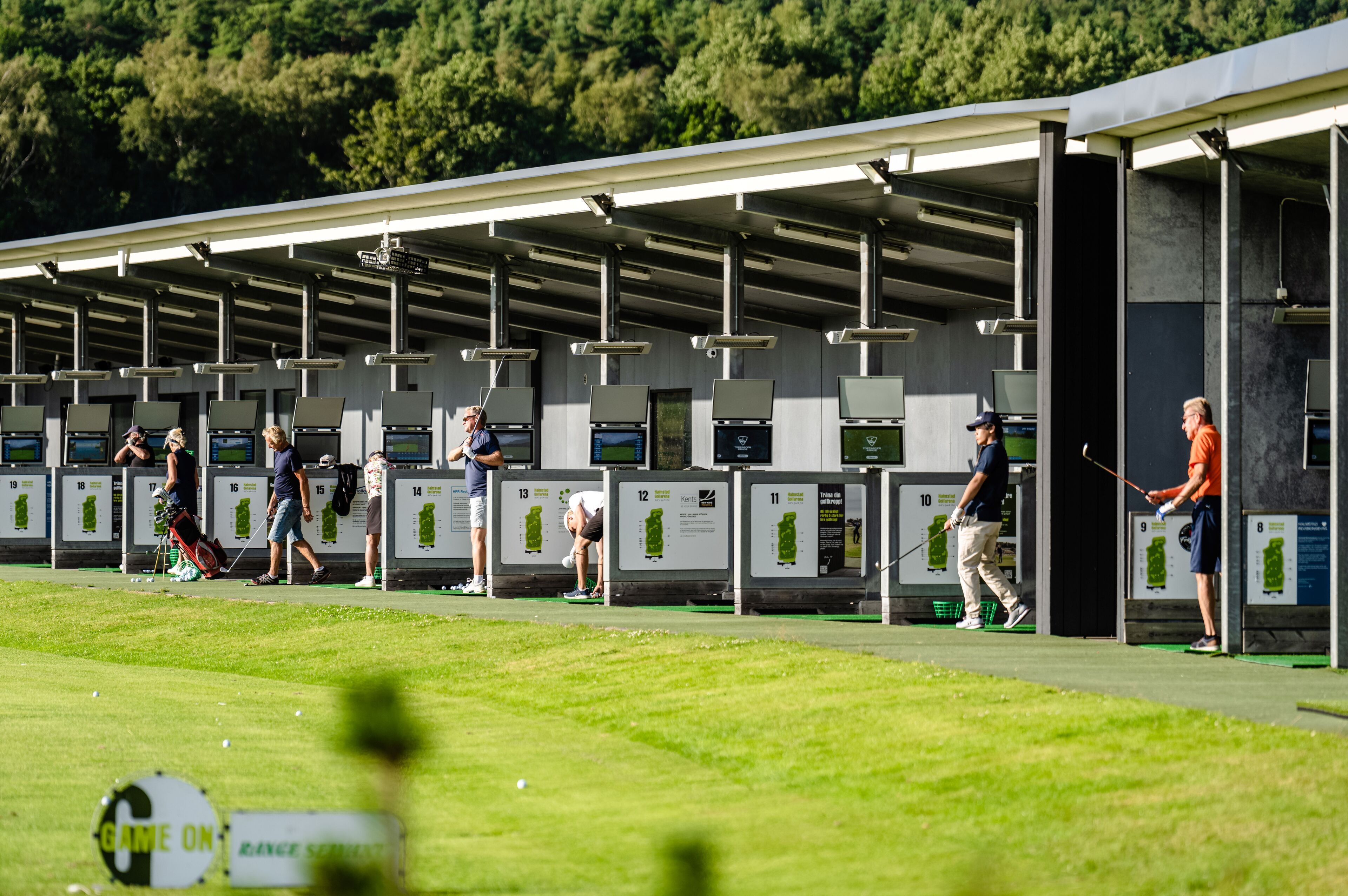 En golf driving range med nummererede tee-bokse og et overdækket område for spillere.