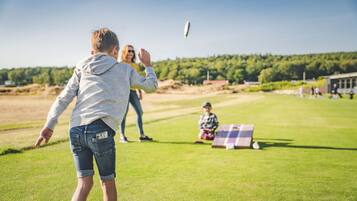 Una persona jugando al frisbee en un campo cubierto de hierba, con cielo despejado.
