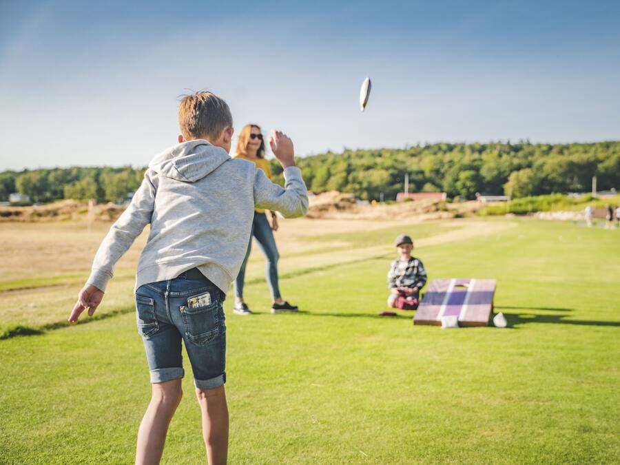 Una persona jugando al frisbee en un campo cubierto de hierba, con cielo despejado.