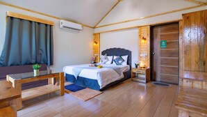 A wooden-floored bedroom with a bed, a nightstand, a glass coffee table, and a sofa.