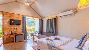 A cozy room with a bed, a desk, a TV, and a small kitchenette.