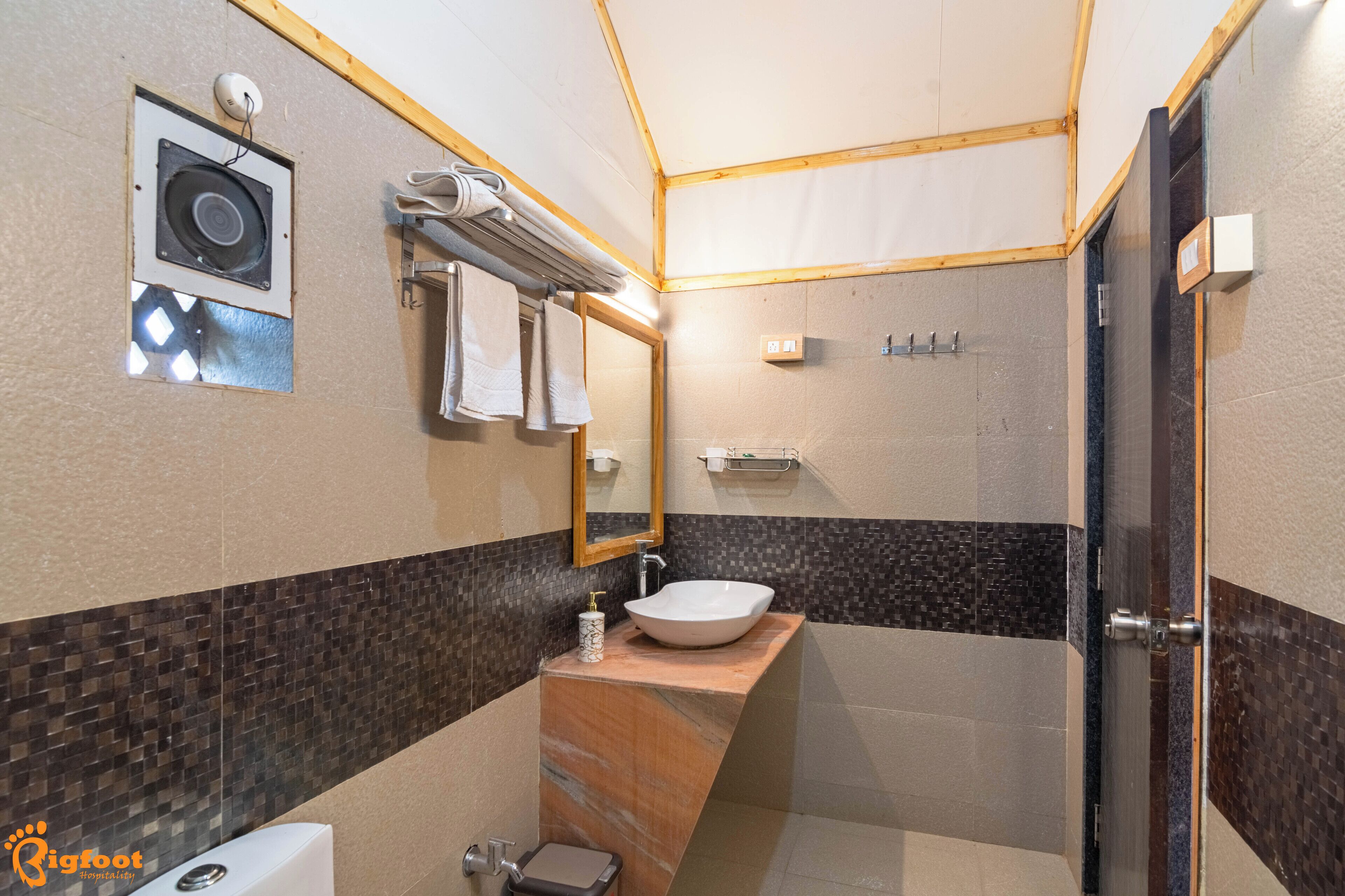 A modern bathroom with a large sink, a mirror, a towel rack, and a shower area.
