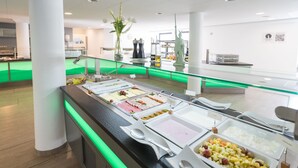 A buffet with various food options, a glass railing, and a statue in the background. - Bildungs- und Tagungshaus Haus Neuland (Bielefeld)