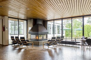 Un amplio espacio interior con una chimenea grande, techo de madera y ventanas amplias que ofrecen vistas al exterior.