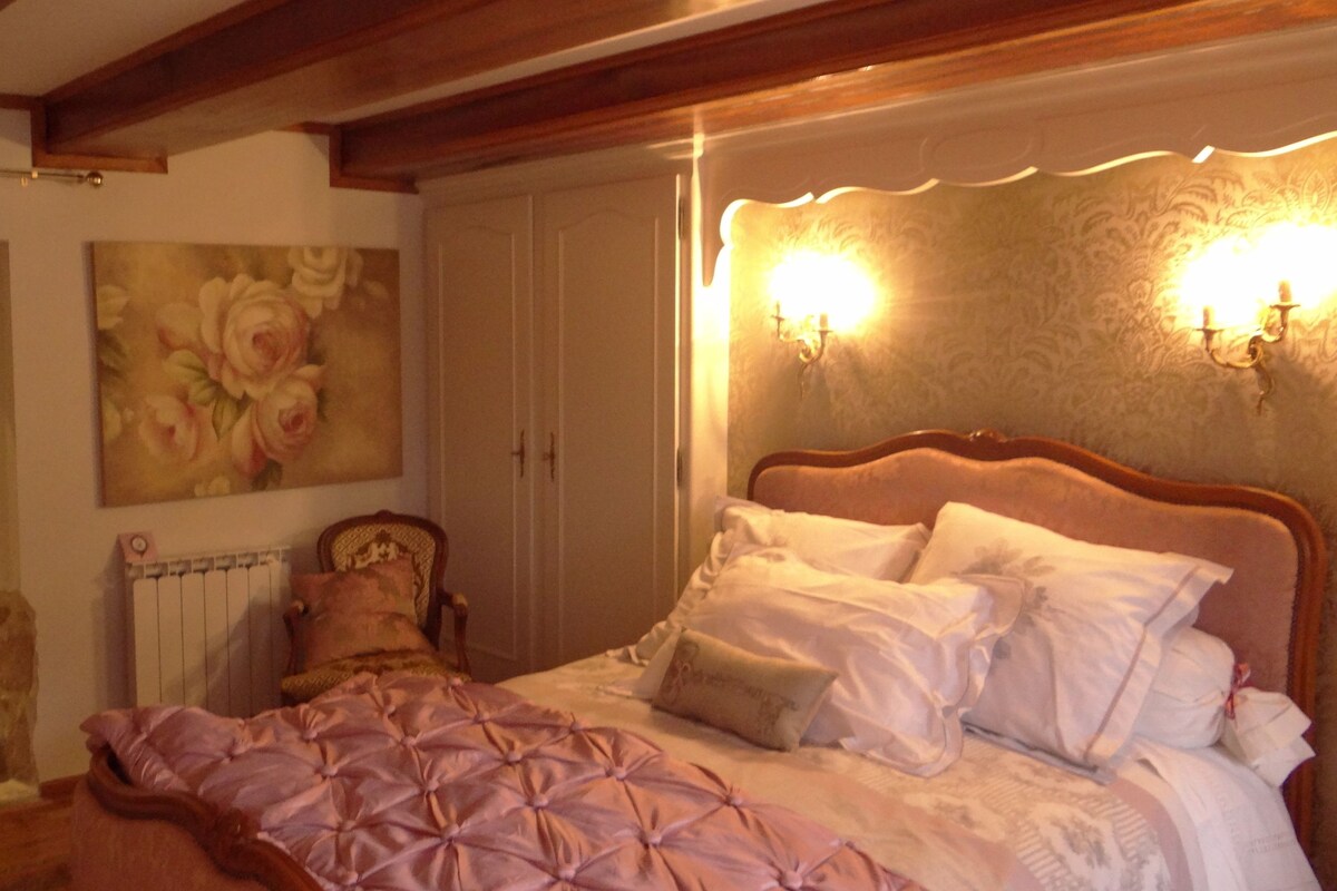 A bedroom with a bed, a radiator, a door, and a painting.