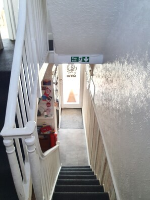 A narrow staircase with white railings and a fire exit sign above. - Lyndale Guest House (Weymouth)