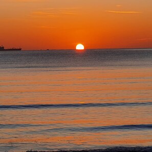 A sunset over a calm sea with a ship in the distance. - Lyndale Guest House (Weymouth)