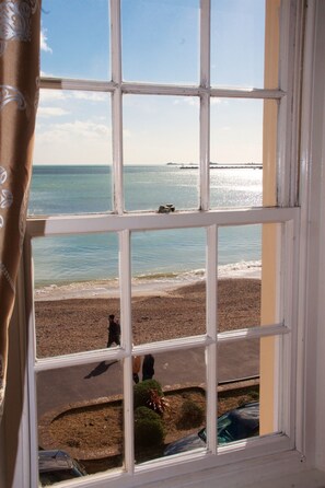 A window view of a beach with a clear sky and calm sea. - Lyndale Guest House (Weymouth)