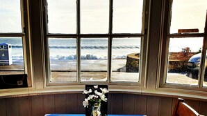 A table with a blue tablecloth, a vase with white flowers, salt and pepper shakers, a mug, and a menu. - Lyndale Guest House (Weymouth)