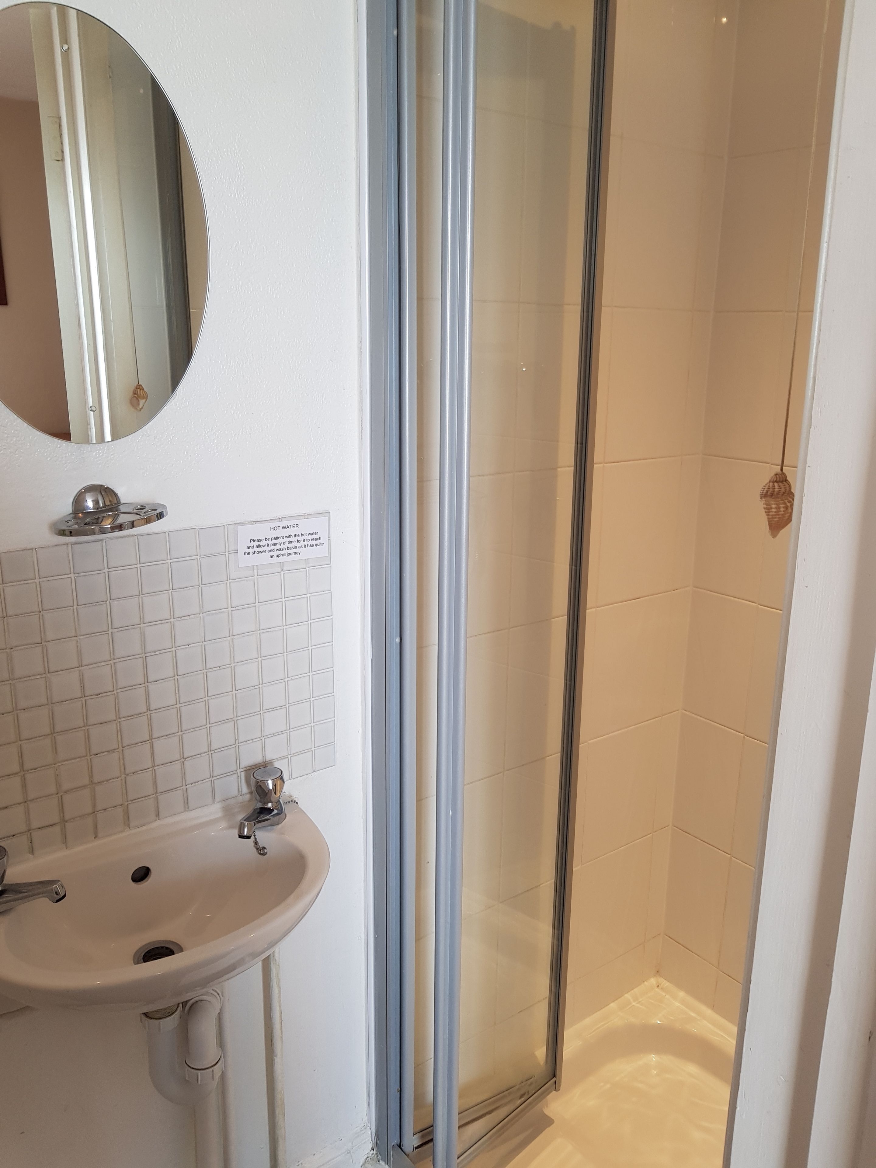 A bathroom with a white sink, a mirror, and a glass shower enclosure.