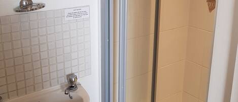 A bathroom with a white sink, a mirror, and a glass shower enclosure.