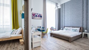 Un dormitorio moderno con una cama de madera, un escritorio con una silla y una pequeña mesa con otra silla.
