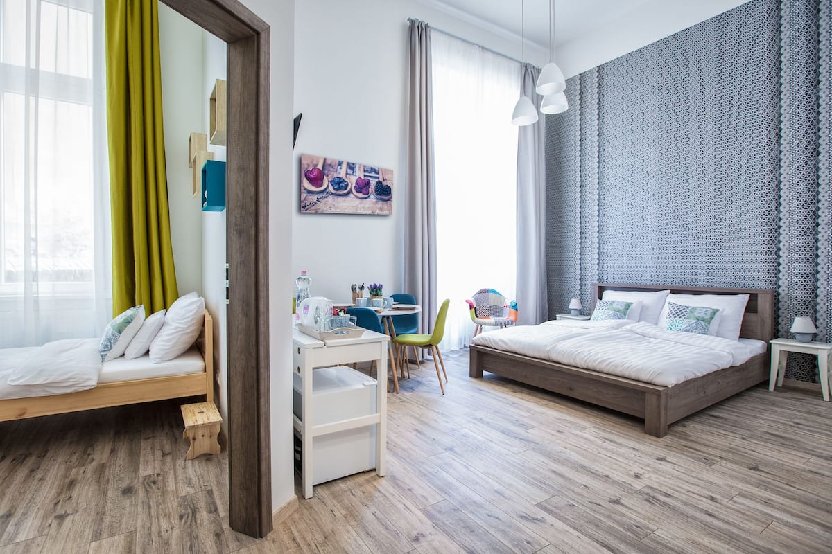 Un dormitorio moderno con una cama de madera, un escritorio con una silla y una pequeña mesa con otra silla.