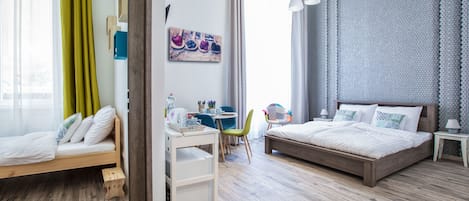 A modern bedroom with a wooden bed, a desk with a chair, and a small table with a chair.