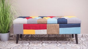 Un banco con diseño de colcha patchwork, una planta en maceta y baldosas estampadas.