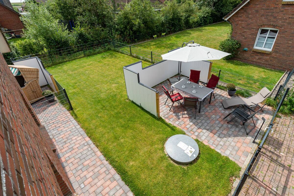 A backyard with a patio area, a table with chairs, a small shed, and a round table with a paper on it.