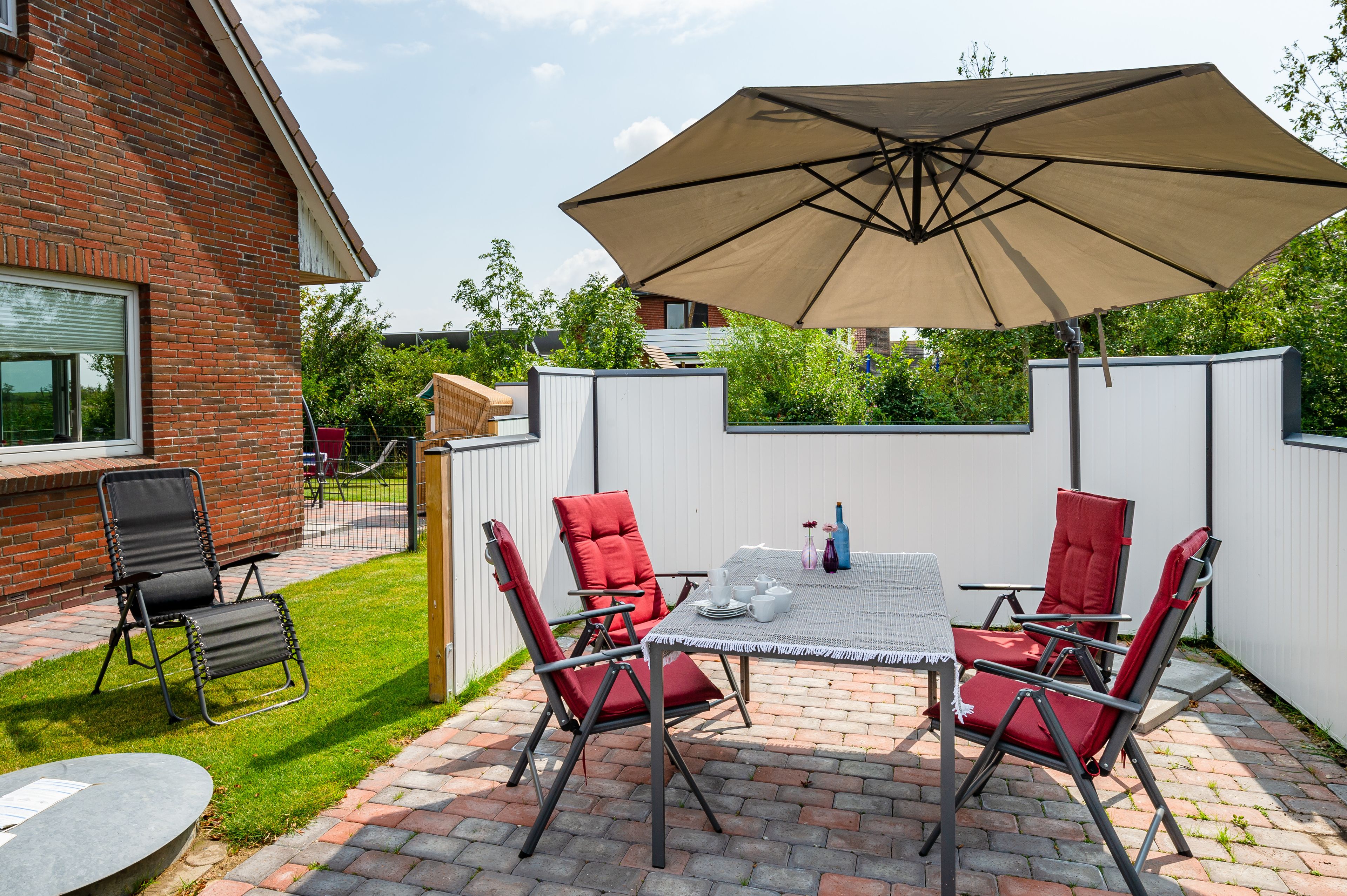 A patio with a table, chairs, and a large umbrella.