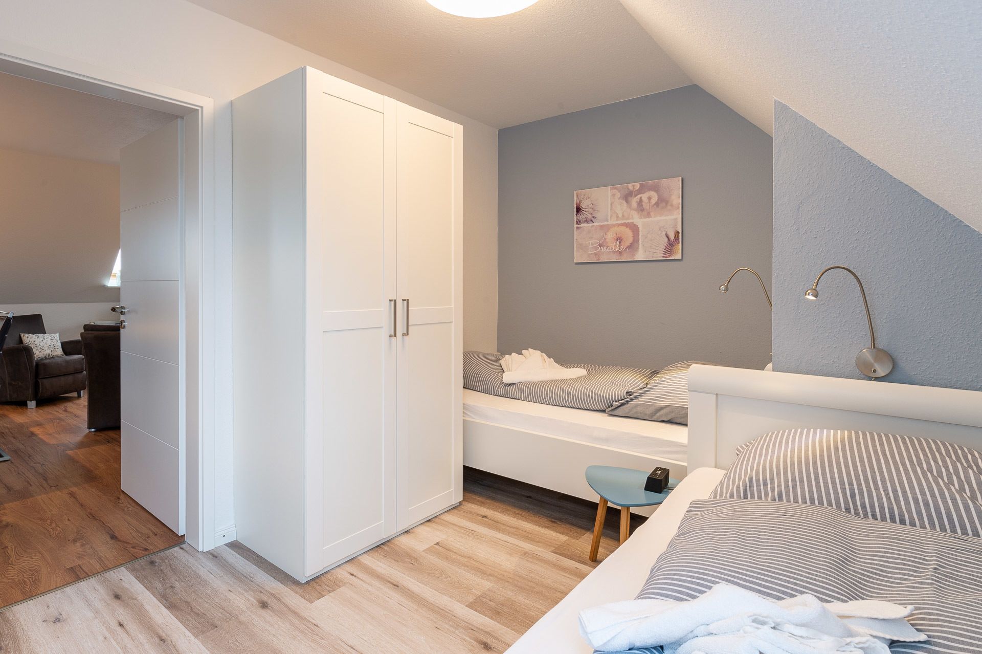 A bedroom with a bed, a bedside table, a chair, a wardrobe, and a painting on the wall.
