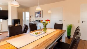 A modern dining area with a wooden table, leather chairs, and pendant lighting. - Haus Bendix (Dagebuell)