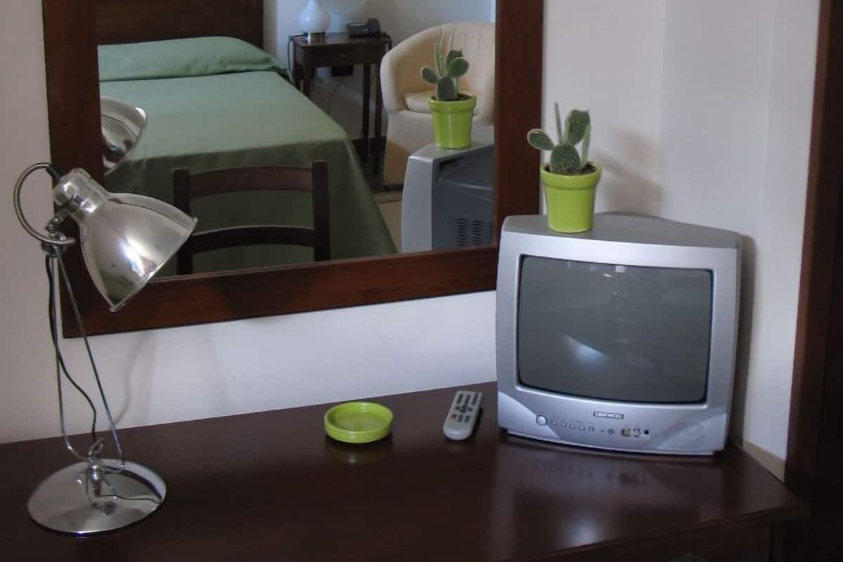 Uma cômoda de madeira com uma televisão, um abajur e duas plantas em vasos.