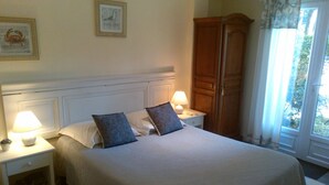 A neatly made bed with two pillows, a nightstand with a lamp, and a wooden wardrobe. - Sous les Pins de Nages (Nages-et-Solorgues)