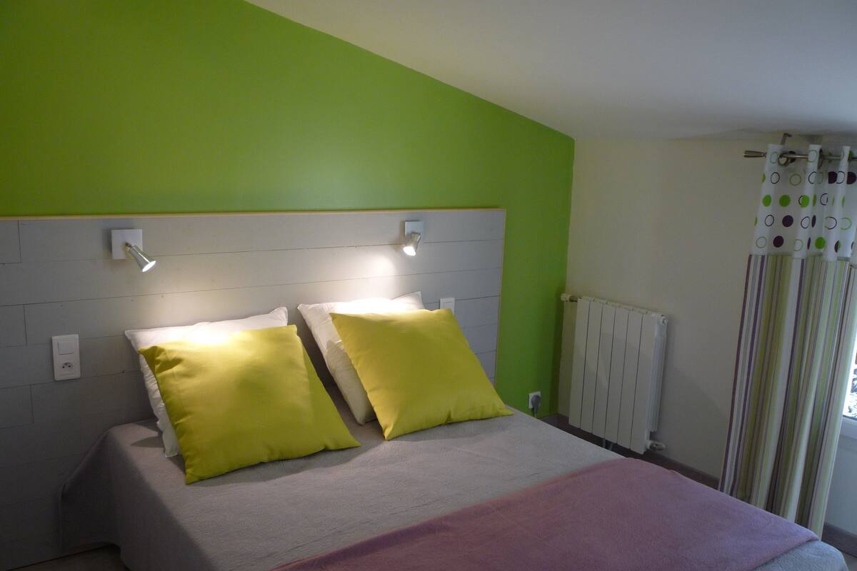 Une chambre à coucher avec un lit, deux lampes de chevet, un radiateur et une fenêtre avec des rideaux.