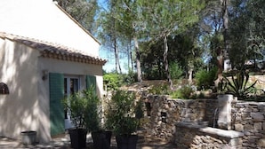 A rustic house with a stone wall, a small garden with potted plants, and a wooden door. - Sous les Pins de Nages (Nages-et-Solorgues)