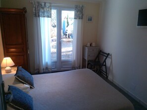 Una camera da letto con un letto, un comodino con una lampada, un armadio in legno, una sedia e un tavolino con delle tazze.