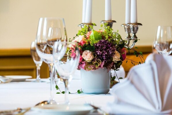 Una mesa dispuesta con copas de vino, un centro de flores y velas.