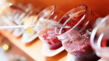 A row of clear glasses filled with a red beverage, likely a fruit punch or juice, on a wooden surface.