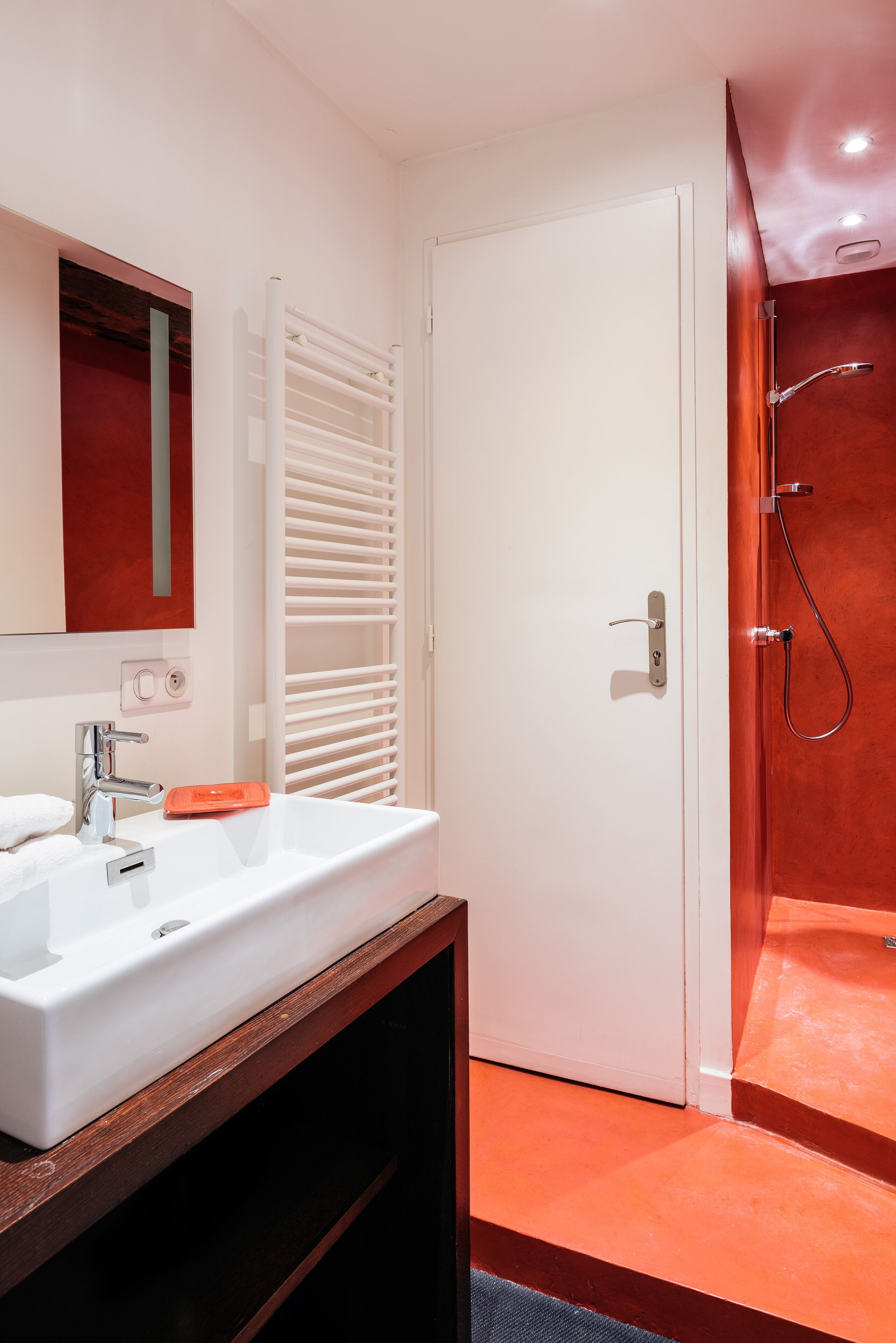 A bathroom with a white sink, a mirror, and a shower area.