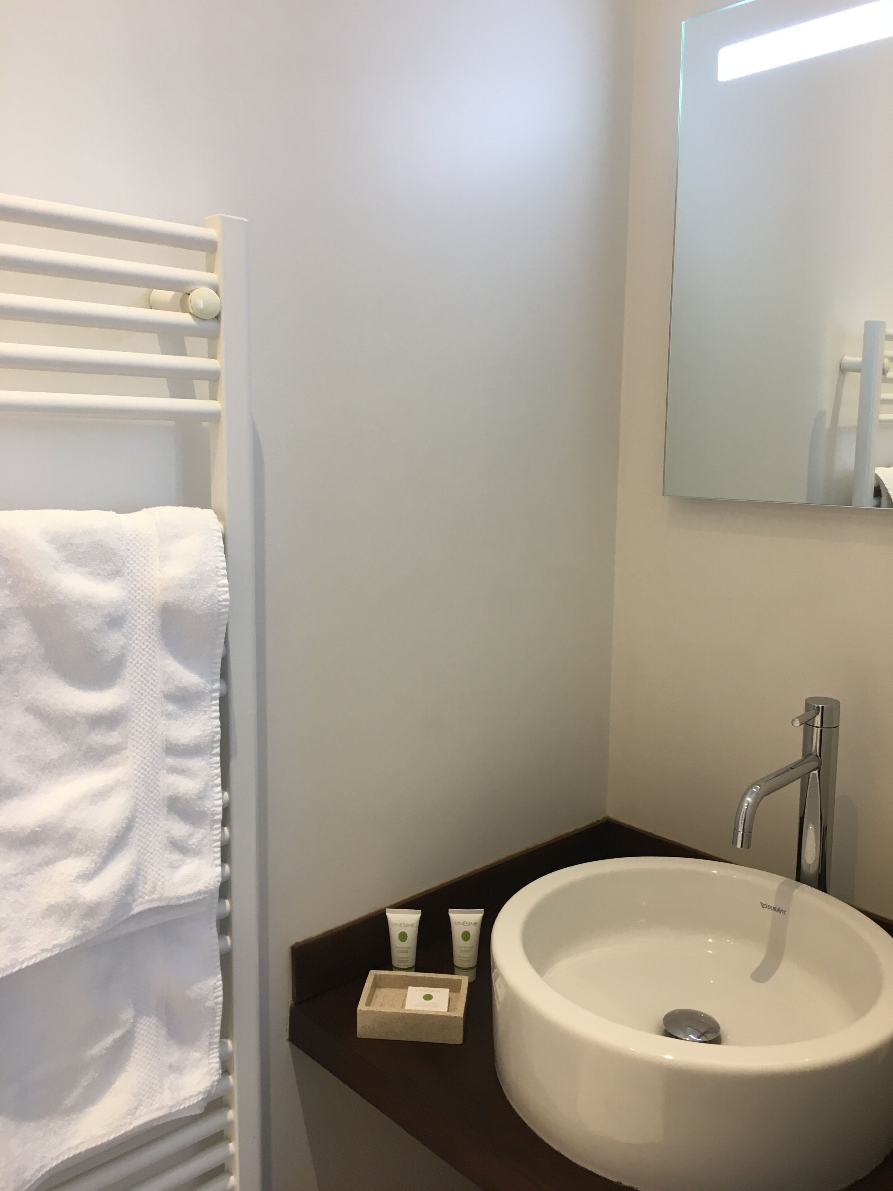 A bathroom with a white sink, a mirror, and a towel rack.
