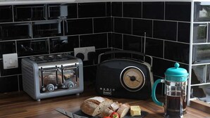 A kitchen with a toaster, a radio, a coffee maker, and a cutting board with bread and strawberries. - High Terrace Apartment (Grantown-on-Spey)