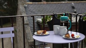 A balcony with a table set for tea, a teapot, and a plate with food. - High Terrace Apartment (Grantown-on-Spey)
