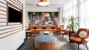 A modern lounge area with a large sofa set, round ottomans, and a wall-mounted TV. - Sydney Suites (Sydney)