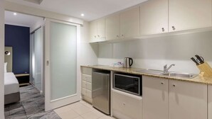 A compact kitchen with a microwave, toaster, and sink. - Sydney Suites (Sydney)