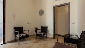 A room with two wicker chairs, a small table, and a door. - B&B Sardinia For You (Oristano)
