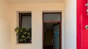 A narrow hallway with tiled flooring, a potted plant, and a door leading to another room. - B&B Sardinia For You (Oristano)
