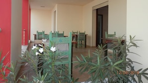 A dining area with green chairs and tables, a red wall, and potted plants. - B&B Sardinia For You (Oristano)