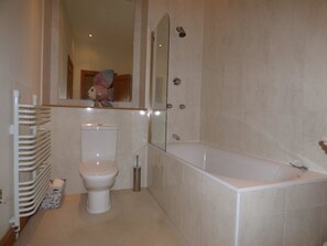 Ein Badezimmer mit Toilette, Badewanne und Spiegel.