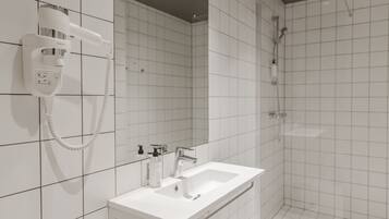 Ein modernes Badezimmer mit einem weißen Waschbecken, einem Spiegel und einem an der Wand befestigten Föhn.