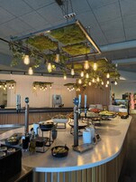 Zona de bufé con diversas opciones de comida, estación de café y lámparas colgantes.