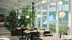 Un restaurante moderno con mesas largas, sillas negras y lámparas colgantes.