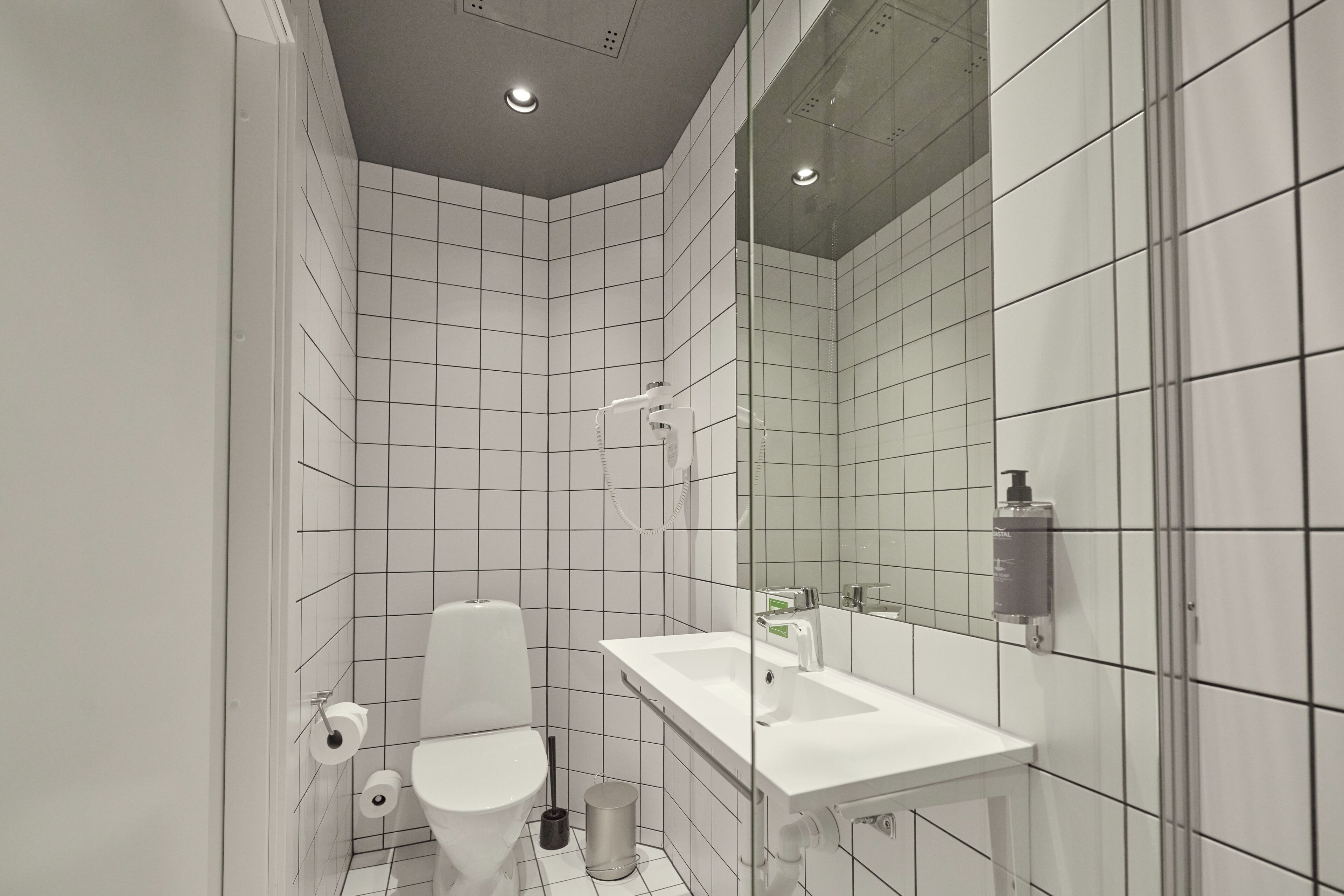 A modern bathroom with a toilet, sink, and mirror.