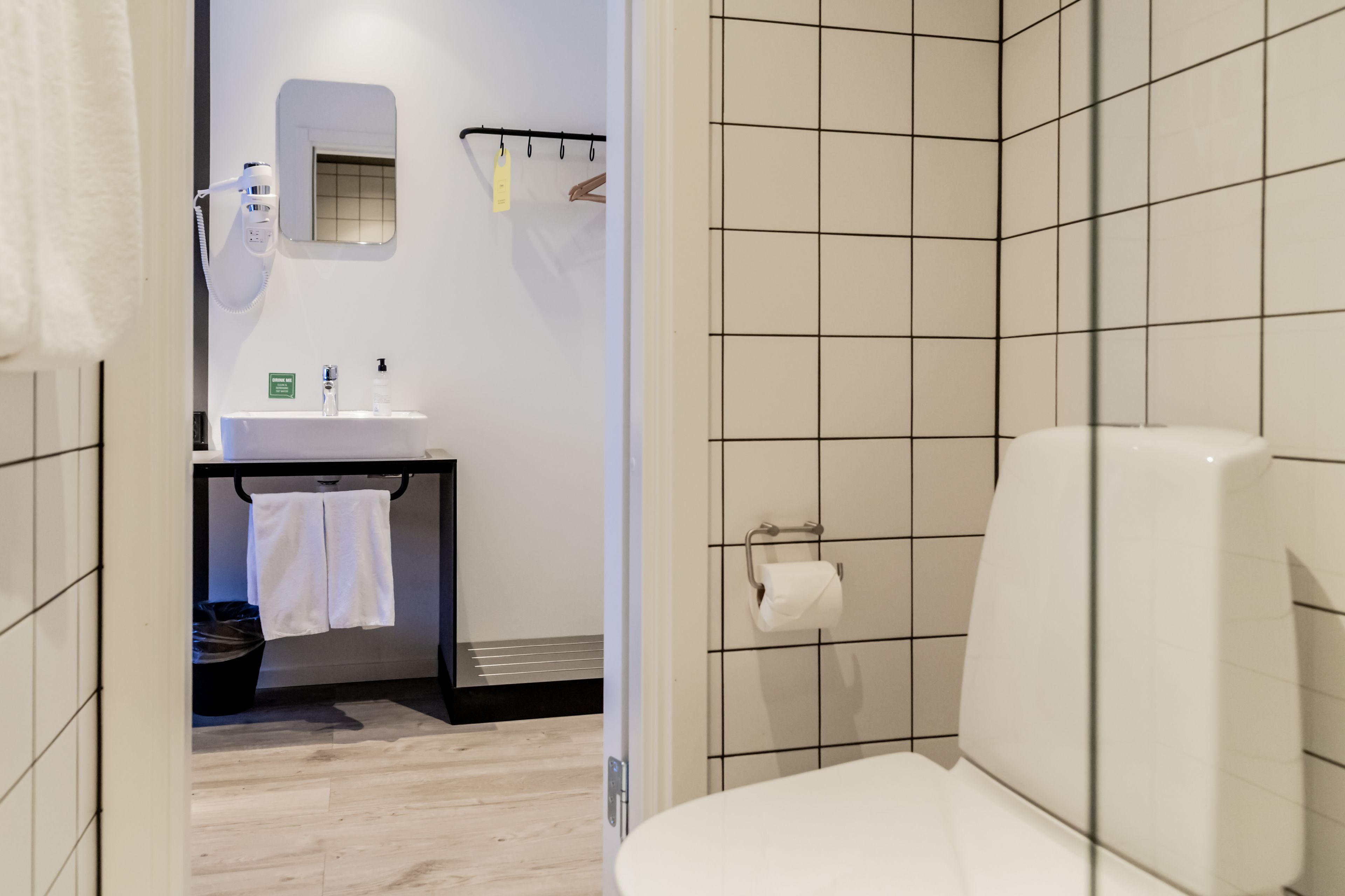 Un bagno con un WC bianco, un lavandino con specchio e un porta asciugamani.